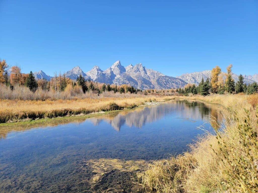 Spectacular mountain range with a serene river, ideal for exploring national parks and outdoor trips.