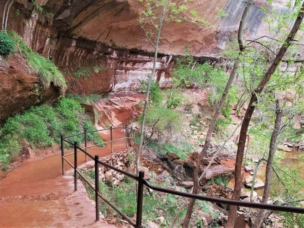 This 2 day itinerary Zion National Park includes the Emerald Pools Trail where this walkway runs under a rock bluff.