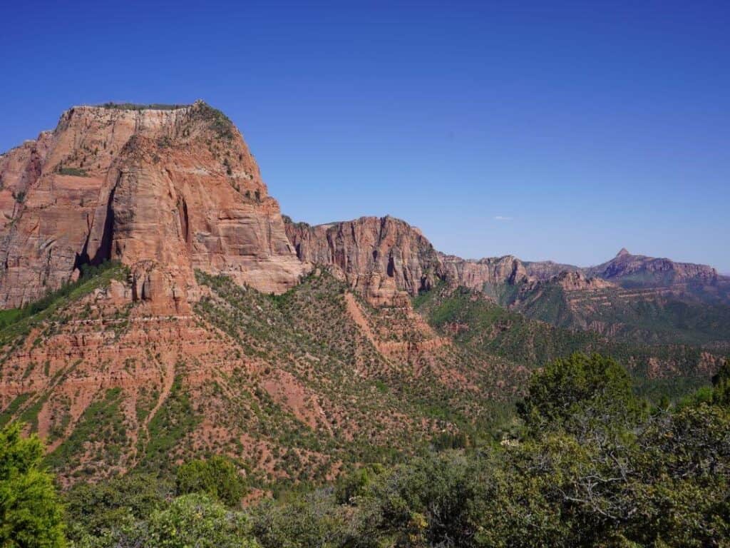 Elevated view of the red hued Kolob Canyons in Zion National park with green foliage at the base.