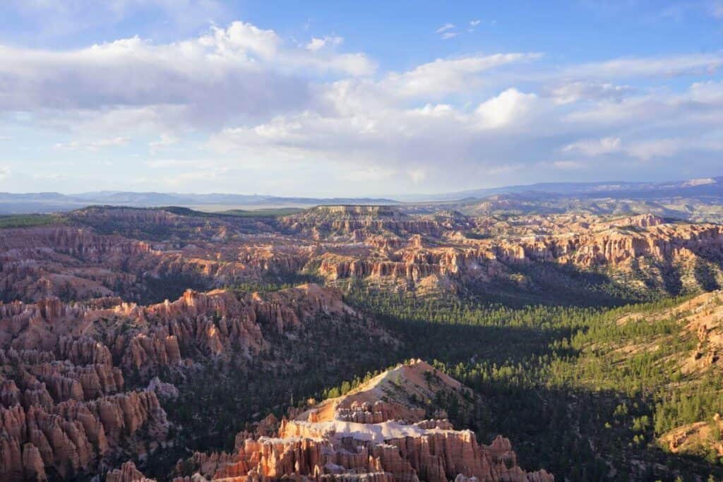 Elevated view looking over the orange hoodoos and green forests in a basin at Bryce Canyon.