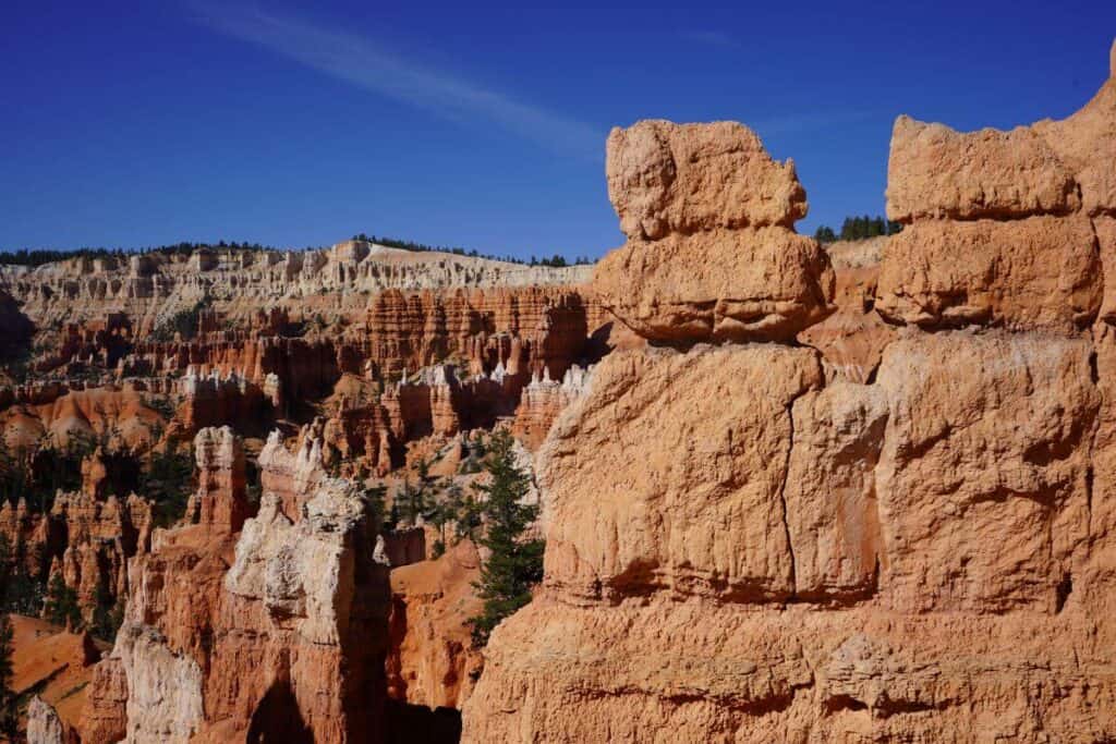 Closeup of an orange rock feature with hoodoos in the background at Bryce Canyon National Park.