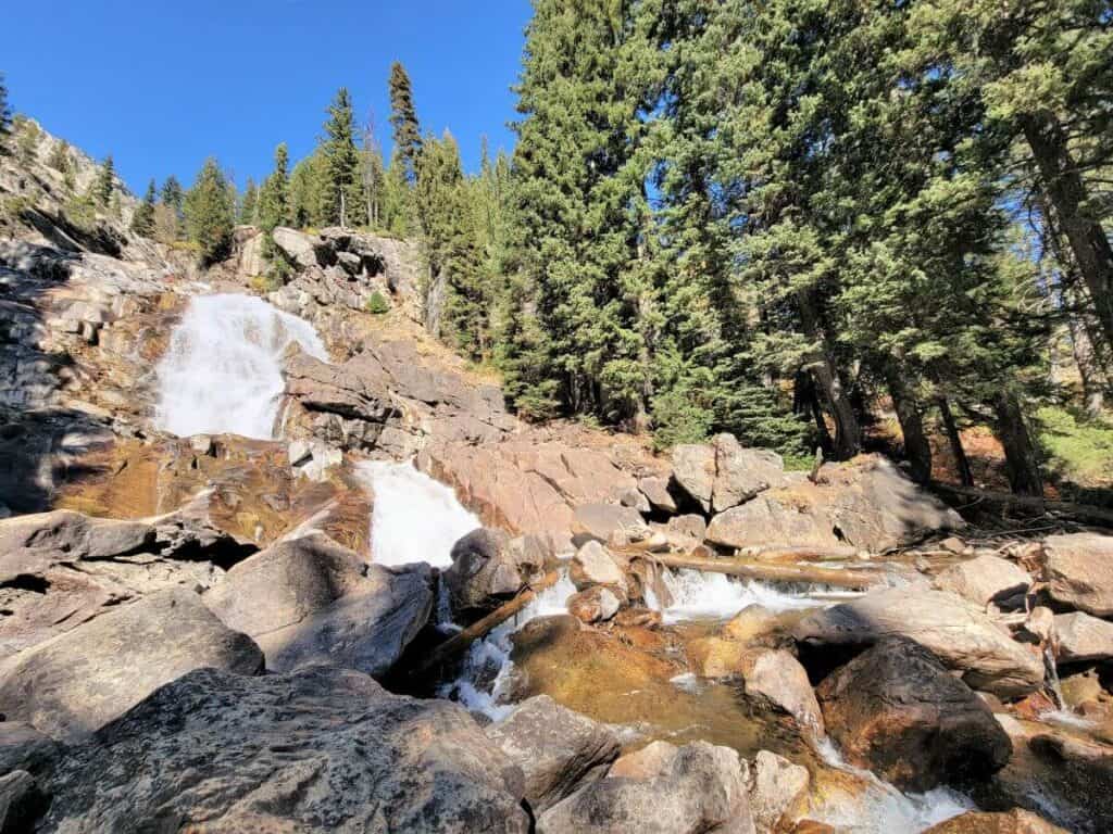 A three tiered waterfall with trees on the bank in Grand Teton Wyoming.